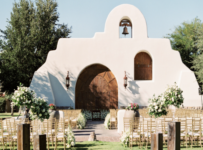 wedding ceremony with chairs set up and flower decor and white architecture building with large wooden door