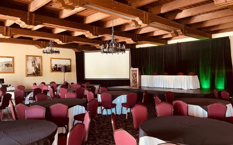 Geronimo会议室，有几张圆弓桌子和红色座椅，配有舞台和投影仪屏幕