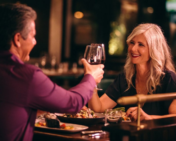 couple clinking their wine glasses over a nice dinner