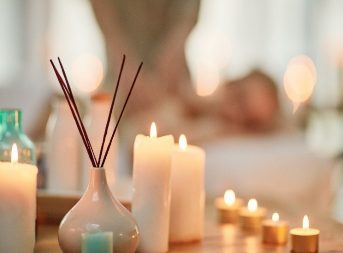 focus shot of candles being lit and person in background getting massage 