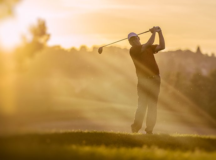 golfer who just swung their golf club with the sunsetting