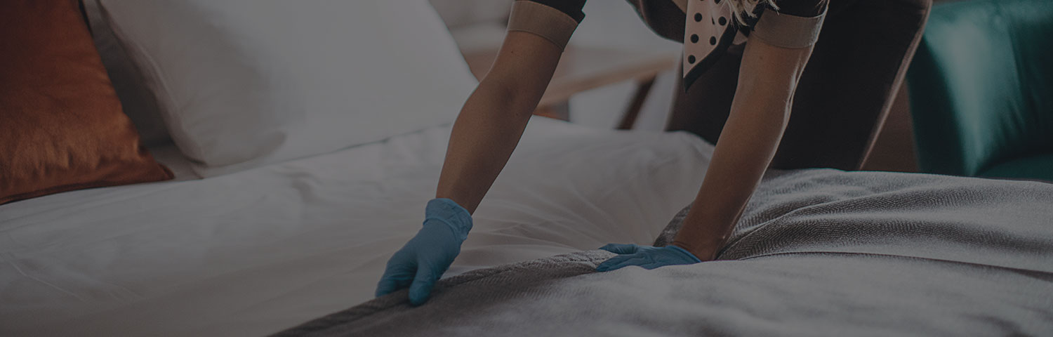 person wearing blue gloves and making the bed
