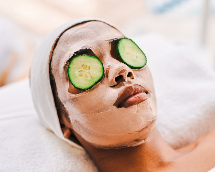 girl getting a facial with cucumber over eyes