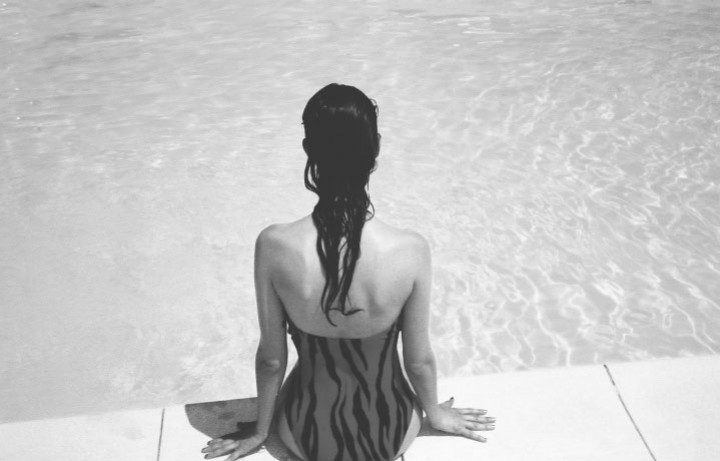 woman sitting on edge of pool
