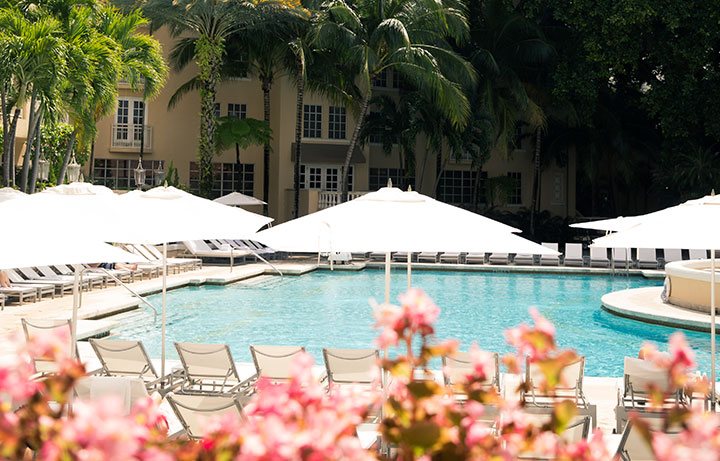 pool with white loungers & pink flowers