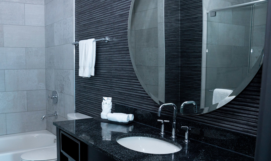 Bathroom vanity area with circular mirror, sink, and towels 
