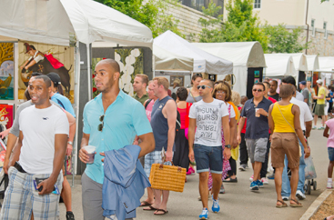 Group of people walking by rows of tents at the outdoor art festival
