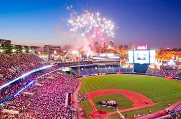 Fireworks shooting off above a crowded baseball stadium 