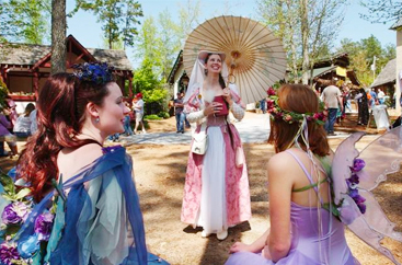 Three women dressed in long dresses with flowers at the Renaissance Festival