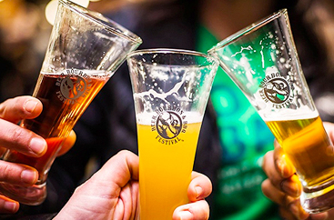 Close up of three people toasting with their beer glasses