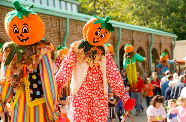 People admiring scarecrows with pumpkin heads at the Pumpkin Festival