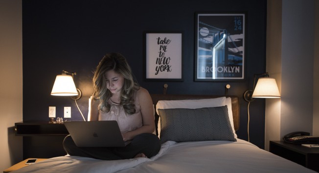 woman sitting on a bed with a laptop