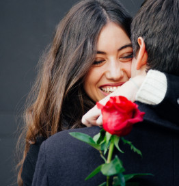 couple hugging female holding red rose