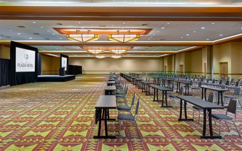 gallery image of a green and red carpet with multiple long tables and chairs