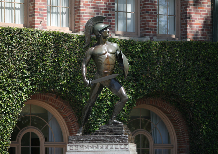 Statue in front of brick building with greenery 
