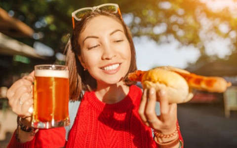 traveler woman drinks mug of beer with hotdog