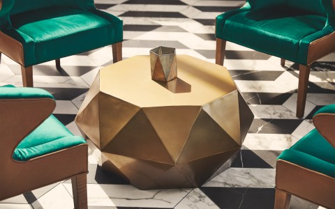 gold geometric center table with teal chairs around it