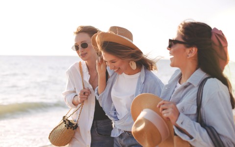 three women walking and laughing by the ocean 