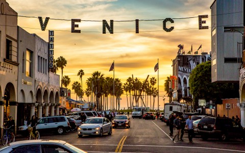 venice sign hanging with sunset in background 