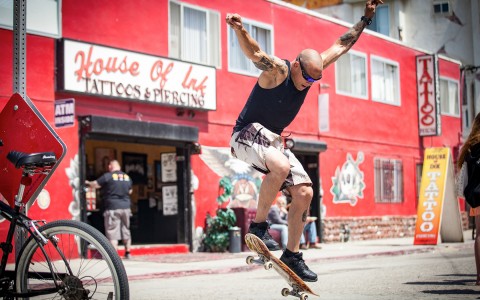 man skateboarding in front of a tattoo shop 