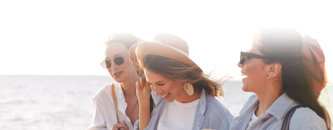 three woman walking and laughing by the ocean