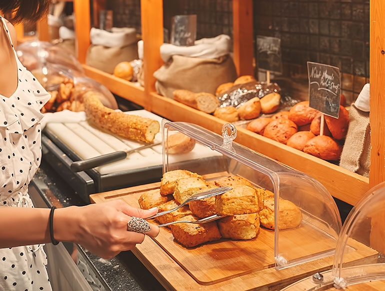 woman picking up a piece of fresh bread at bakery