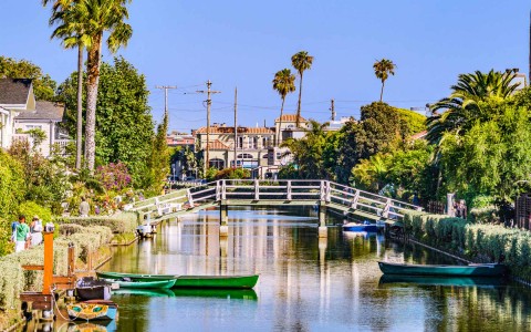 view of venice canal with canoes in it and a white bridge crossing it 