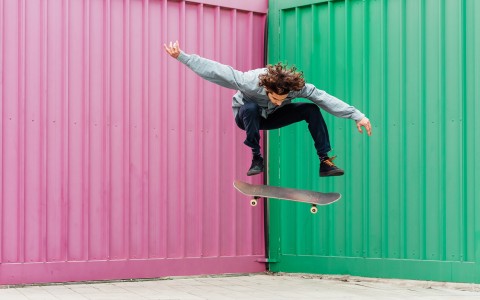 a person skateboarding in front of a pink and green background