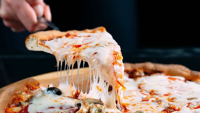 fresh pizza being cut in slices