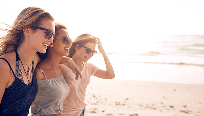 three women walking and laughing by the ocean
