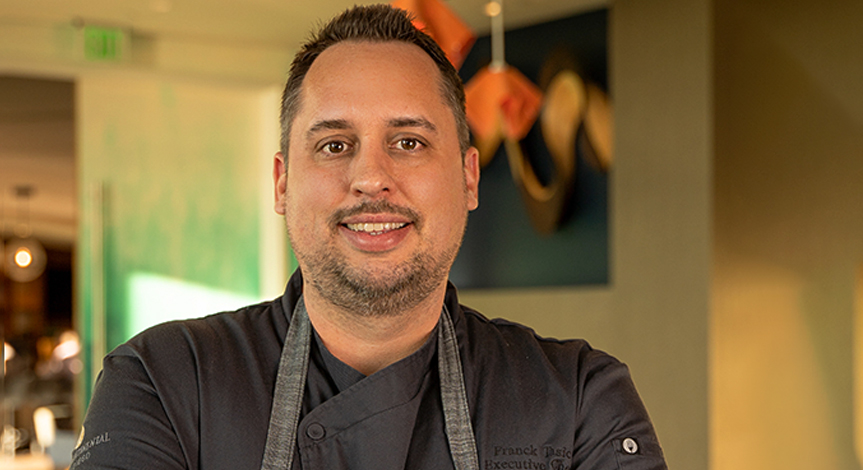 Head shot of Chef Franck Tasic posing in black chef's apron