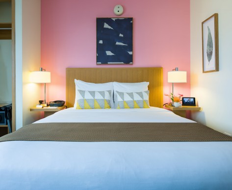 cosmopolitan room with queen bed and pink wall 3