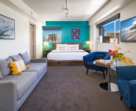 lifestyle junior suite with king bed, one blue wall, and to the right is a blue chair for the seating area
