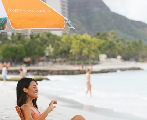 woman sitting chair with orange umbrella at the beach