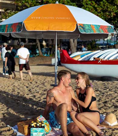 couple on the beach under a white and orange umbrella
