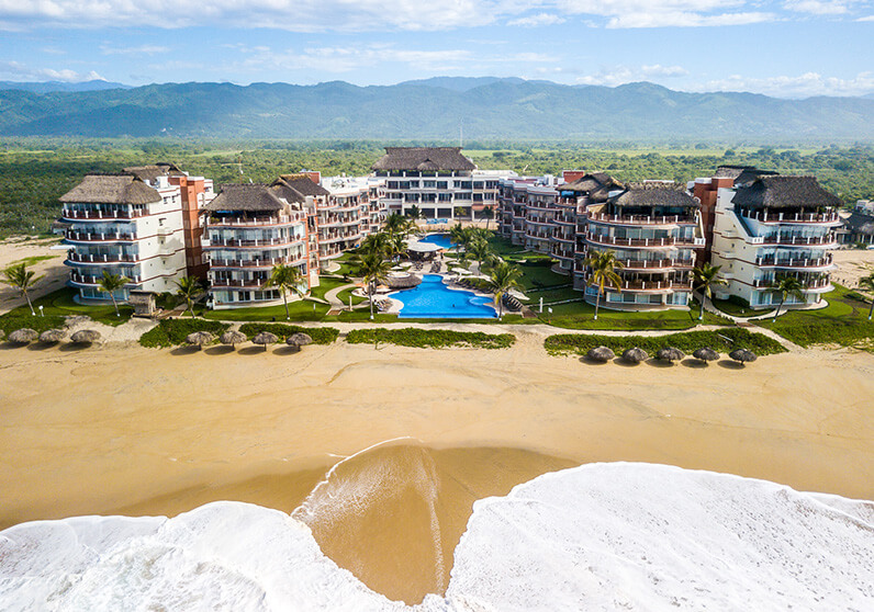 aerial view of the entire vivo resort with the beach waves crashing towards it