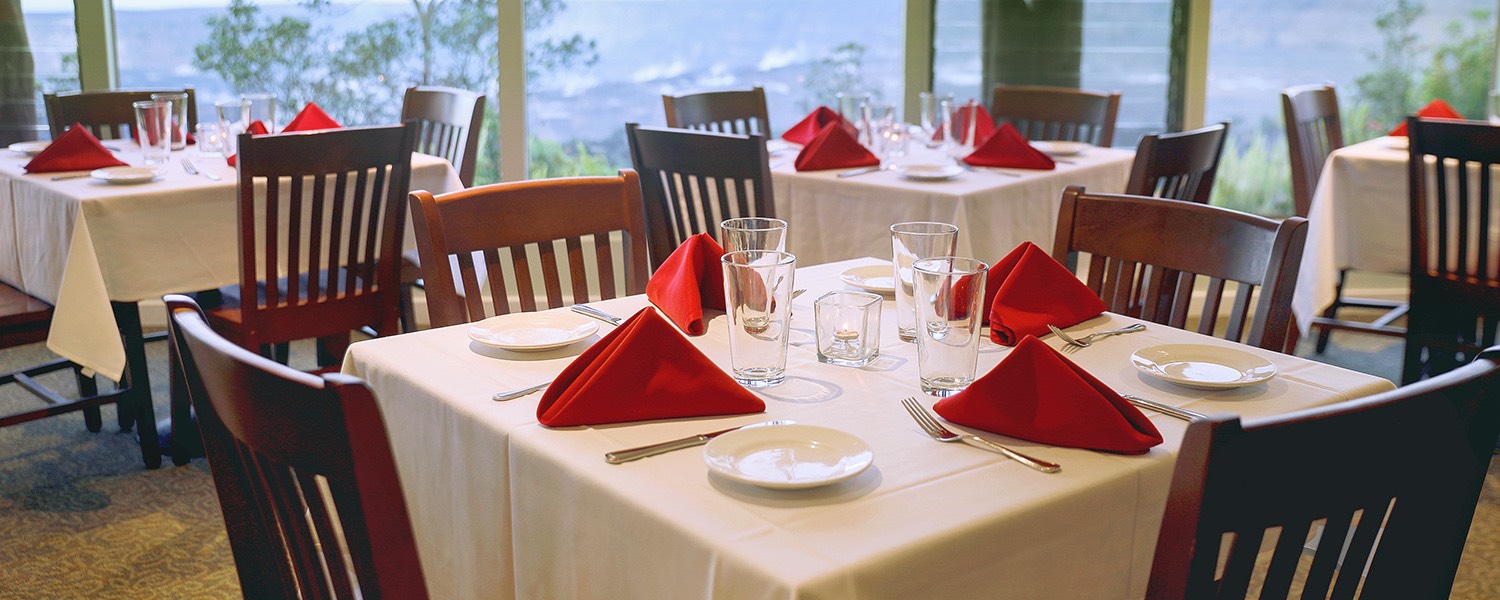 square tables with white tablecloths and red napkins