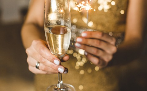 woman in gold dress holding sparkler and champagne glass