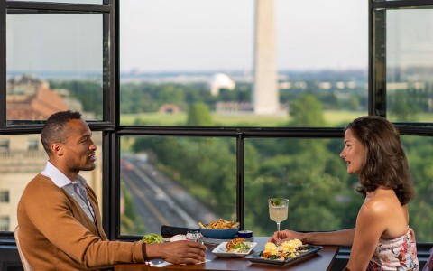 man and woman enjoying dinner with the washington monument in the background