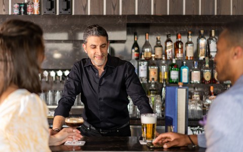 bartender serving a beer to 2 customers
