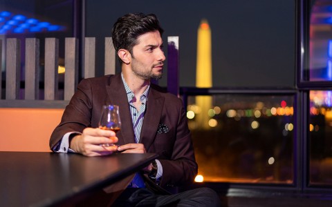 man looking to his right holding glass of liquor