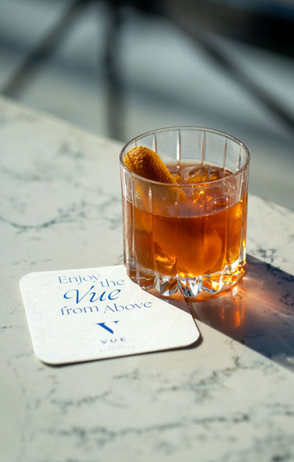 orange cocktail with VUE coaster below it