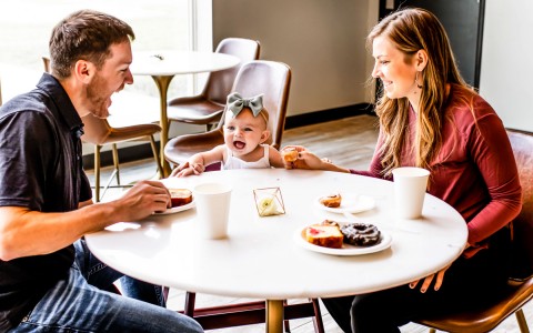 parents sitting looking at them child with some food in the table