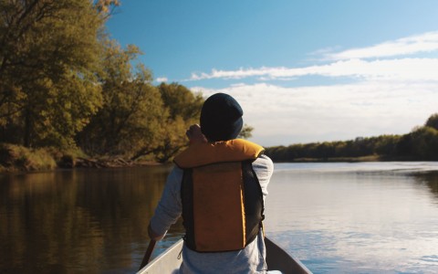 Back of a guy enjoying the day in a canoe