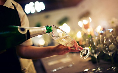 closeup view of a waiter filling a glass of champagne up