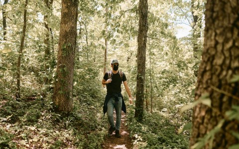 Guy wearing a face mask walking in the middle of the nature 