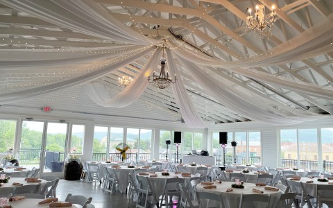A big dining area decorated for an special event with elegant lamps and white tables