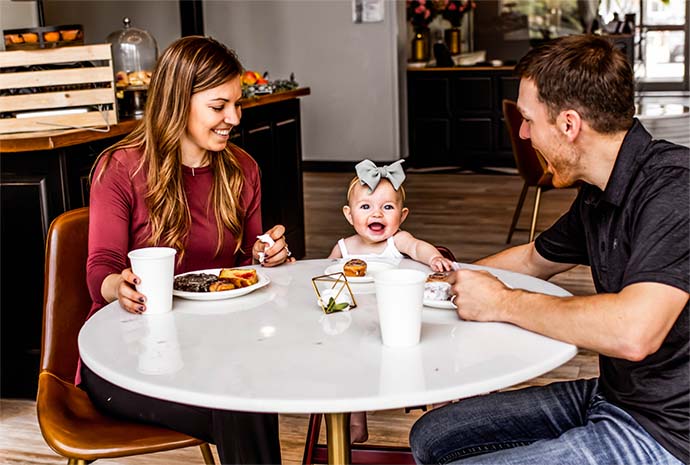 A lovely couple sitting on the dining area and laughing with their cute baby girl