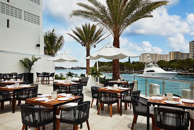 Outdoor dining area with wooden tables & chairs by water