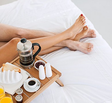 Couple legs intertwined with breakfast in bed